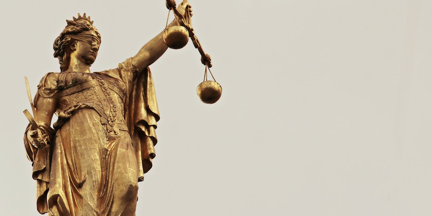 Statue der Justitia mit Schwert und Waage in den Händen